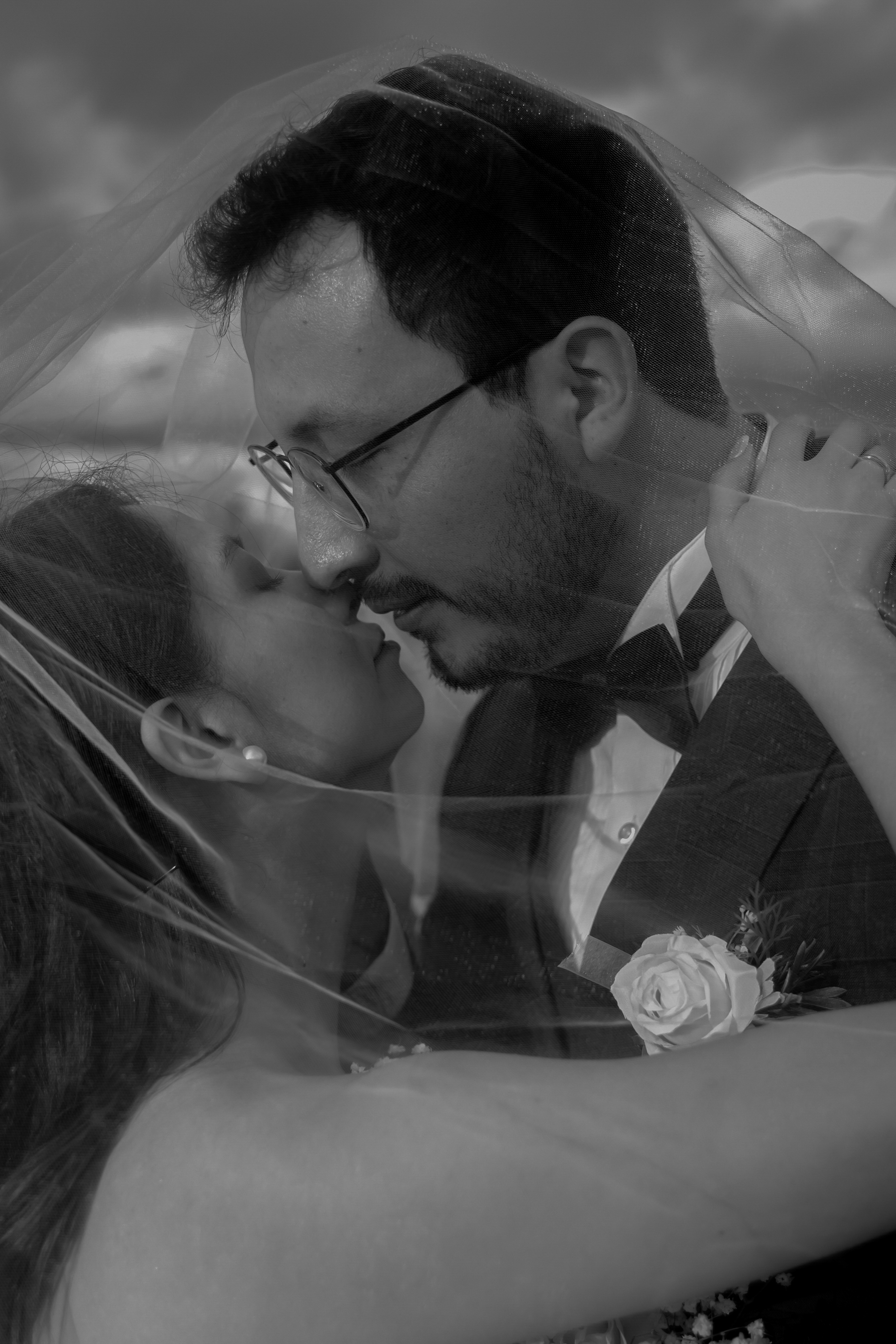 portrait of wedding couple covered by the bride veil