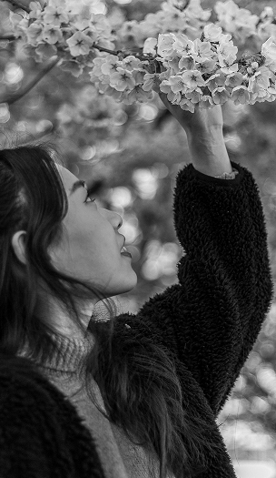 portrait of girl reaching for a cherry blossom flower