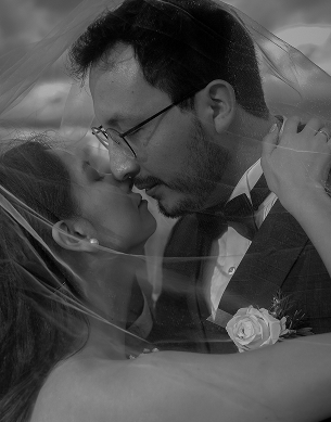 portrait of wedding couple covered by the bride veil
